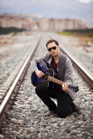 Young handsome musician playing his blue guitar.の写真素材