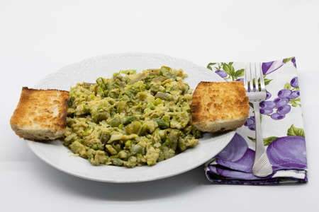 Scrambled wild asparagus and eggs in a white ceramic dish isolated on a white backgroundの写真素材