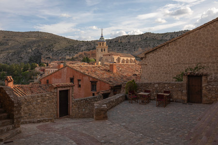 Picturesque terrace in the village of Albarracin with stone walls, mountain views, and rustic rooftops at sunset.の写真素材