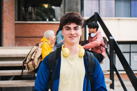 Portrait of a college student carrying a backpack and standing on steps outdoorsの写真素材