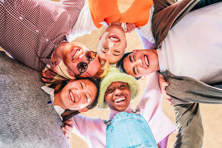 Low angle view of young multiethnic friends standing together smiling and having fun.の写真素材