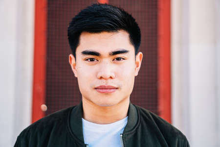 Portrait of serious asian guy looking at camera outdoors.の写真素材