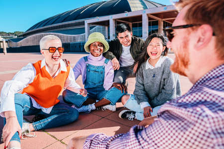 young group of friends laughing sitting together on the floor outdoor.の写真素材