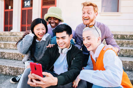 group taking a selfie photo with a smartphone sitting on the floor.の写真素材