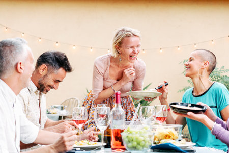 Mature people celebrating a bbq party sharing his food with his friends. Pretty woman brings a salad to the table. Lifestyle concept.の写真素材