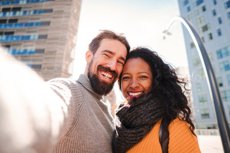 Portrait of smiling young multiethnic couple taking selfie photo with a mobile phone while doing a...