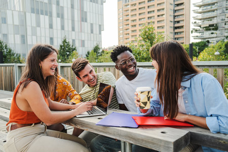 Multiracial smiling group of five teenagers students using laptop doing homework and enjoying a...