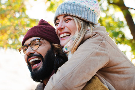 Close up portrait of lovely couple hugging. Young bearded man with glasses giving his blonde cute girlfriend a piggyback rideの写真素材