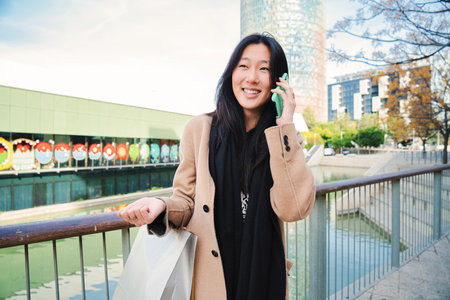 Young asian woman having a friendly phone call conversation outdoors. One chinese girl smiling and talking by cellphone. Communication conceptの写真素材