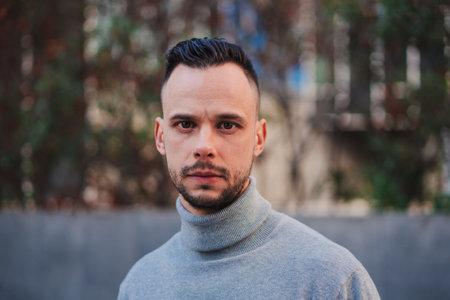 Front view of one serious male looking pensive at camera. Close up portrait of young entrepreneur man standing isolated outdoors. Head shot of thoughtful guy thinkingの写真素材