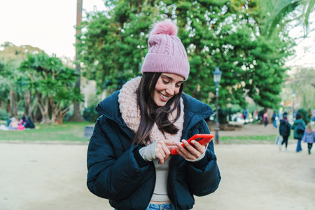 One caucasian woman smiling typing with a cell phone in a social media app. Front view of a teenage girl using a smartphone for send messages to her friends. Communication concept.の写真素材