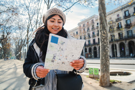 One young asian tourist woman looking for directions in a paper map visiting a european city on a weekend. Front view of a lady watching a location on a guide in a vacation trip. Travel concept.の写真素材