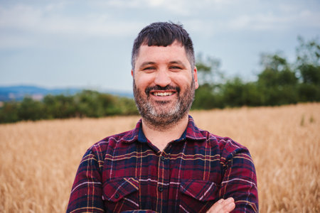 Close up portrait of one happy farmer man smiling and looking at camera with pride attitude at in a wheat field. Agricultural conept.の写真素材