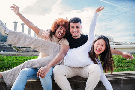 A group of young multiracial people having fun together. Three mixed teenagers smiling looking at...