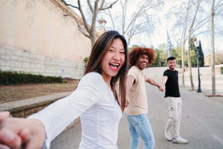 Point view portrait of a multiracial group of friends walking holding hands. pov of young people having fun running hand in hand. First person perspective of three happy teenagersの写真素材
