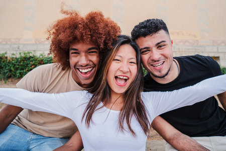 Portrait of a group of multiracial teenagers laughing and smiling together. One asian young woman spreading arms and having fun with her male friends. Happy and excited peopleの写真素材