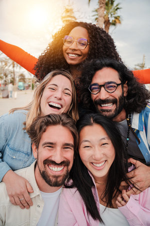 Vertical portrait of a group of friends laughing together and looking at camera. Five young multiracial people smiling and having fun. Joyful startup team coworkers celebrating andの写真素材