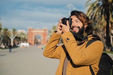 Happy tourist photographer smiling and shooting a photo in Barcelona street. Young traveler focusing...