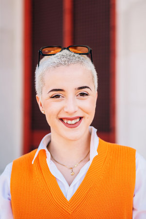 Vertical individual portrait of happy blonde teenage girl looking at camera. Young adult real woman laughing and smiling with friendly expression outdoors. One youngster cheerfulの写真素材