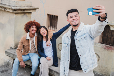 A group of teenage students taking a selfie portrait with a smartphone. Three young adult friends...