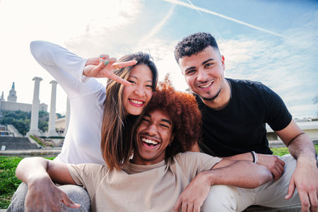 Group of young multiracial friends hugging and having fun together. Three happy cool buddies smiling and looking at camera. Diverse joyful student teenage people laughing bondingの写真素材
