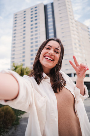 Vertical portrait of pretty young adult woman with thooty smile having fun taking a selfie using a social media. Happy teenage female laughing and looking at camera with cheerfulの写真素材