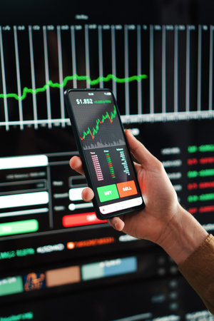 Vertical portrait of crypto trader broker using a cell phone financial app to buy or sell shares of stock market. Investment concept. Hand holding a smartphone with bankingの写真素材