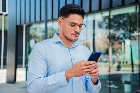 Portrait of handsome startup business man or clerk using a cellphone to send email or read news. Office worker browsing on internet with a smartphone with serious expressionの写真素材