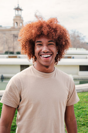 Individual portrait of one joyful african american guy with afro hair looking at camera with friendly expression. Young high school student man smiling. Teenager male laughingの写真素材