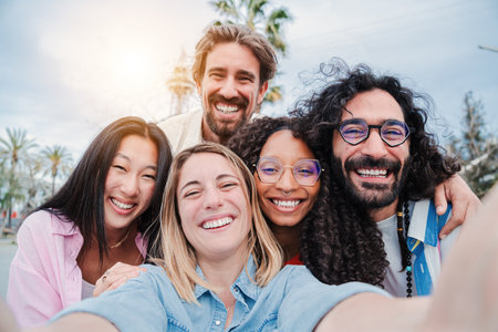 Group of joyful best friends having fun and laughing taking a selfie portrait together. Friendly young adult people smiling and looking at camera outside. Multiracial buddies on aの写真素材
