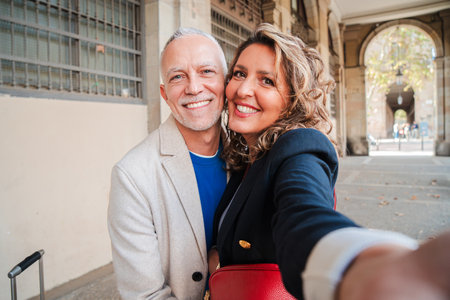 Affectionate mid adult married couple having fun taking a selfie portrait together on a romantic date. Real middle aged friends smiling and laughing. Gray hair husband and wife onの写真素材