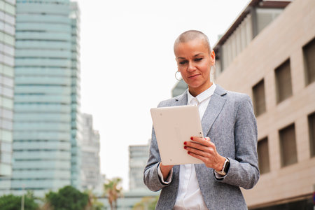 Confident businesswoman using a wireless tablet to work on a downtown workplace. Executive business female with a touchpad browsing on internet with a communication app. Successfulの写真素材