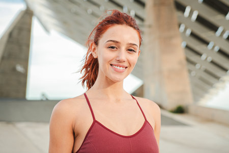 Close up individual portrait of one redhead female smiling and looking at camera outside. Young adult woman with friendly expression staring frontの写真素材