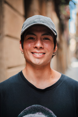 Vertical individual portrait of one hispano male smiling and looking at camera with a urban cap. Young adult latin american guy staring front andの写真素材