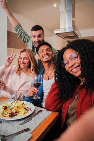 Vertical. African american young woman having fun taking a selfie portrait with her friends at lunch party. Group of people drinking red wine, diningの写真素材