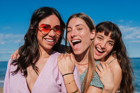 Group of only women taking a selfie portrait on the beach on her summer vacations. Female friends having fun together and enjoying a shore tripの写真素材