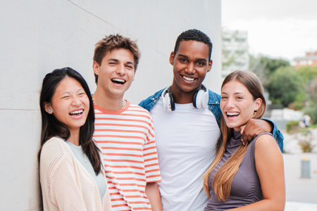 two handsome men and two teenage women looking at camera standing at university campus. Group of...