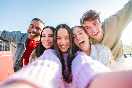 Selfie portrait of a group of young multiracial teenagers having fun on a friendly meeting. Five mixed friends smiling and laughing. Students lookingの写真素材