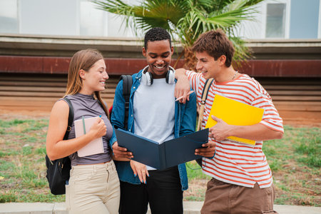 High school student smiling while showing his two colleagues the homework and lesson for the exam. Three multiracial friends reading, checking testの写真素材