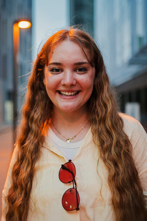 Vertical portrait of a real young woman looking at camera. One happy female smiling and staring front at night. Optimistic teenage girl with friendlyの写真素材