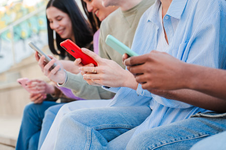 Close up cut out portrait of the hands of a group of young people using their cellphones to browse...