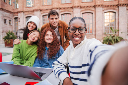 African american teenage student taking a selfie with her friends using a smart phone. Group of multiracial classmates taking a portrait with aの写真素材