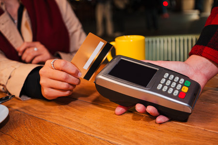 Close up portrait of a unrecognizable customer hand using a credit card for contactless payment on a...