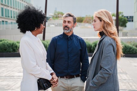 Three professionals engaged in discussion outdoors showcasing collaboration and communication. Group...