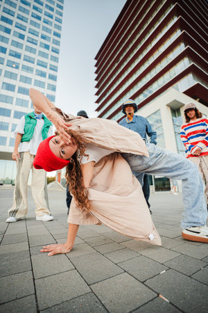 A Talented B-Girl Displays Her Incredible Breakdance Skills While Executing a Stunning Freeze Move. The Group of Dancers Supports Her Performance withの写真素材