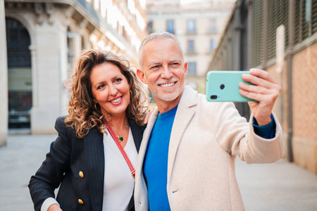 Joyful Mature Couple Taking a Selfie with a Smartphone in the City, Capturing Moments Together, Radiating Happiness and Connection in Their Smiles andの写真素材