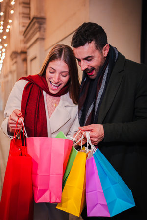 Excited Couple Enjoying Their Shopping Experience Together While Opening Colorful Shopping Bags on a Joyful Evening Out Filled with Delight andの写真素材