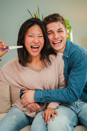 Vertical. Joyful couple celebrating the exciting news of a positive pregnancy test with bright...