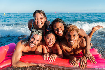 Joyful group of friends having fun together in the sun at a beautiful beach during summer vacationsの写真素材