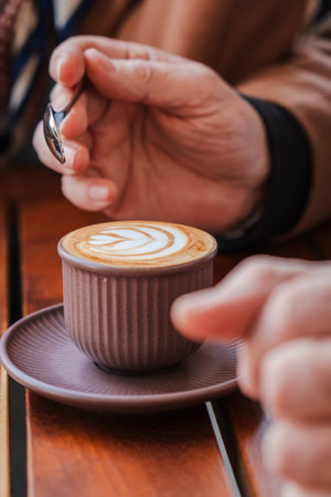 A delightful cup of freshly brewed coffee with intricate latte art being enjoyed with a spoon in hand, showcasing a luxurious moment of relaxation andの写真素材
